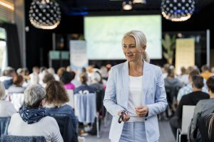 Kerstin Hardt in einem blauen Blazer vor einer Menschenmenge bei ihrem Vortrag zu dem Weg aus Angst und Deppression